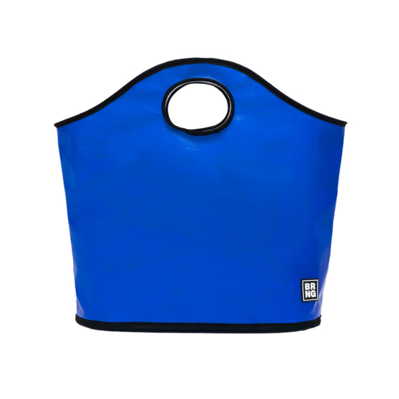 The James Tote by BRNG Bag is a large, bright blue fashion tote with a rounded top, circular cutout handle, black trim, and a small black-and-white BRNG logo patch—an all-purpose bag perfect for daily style.