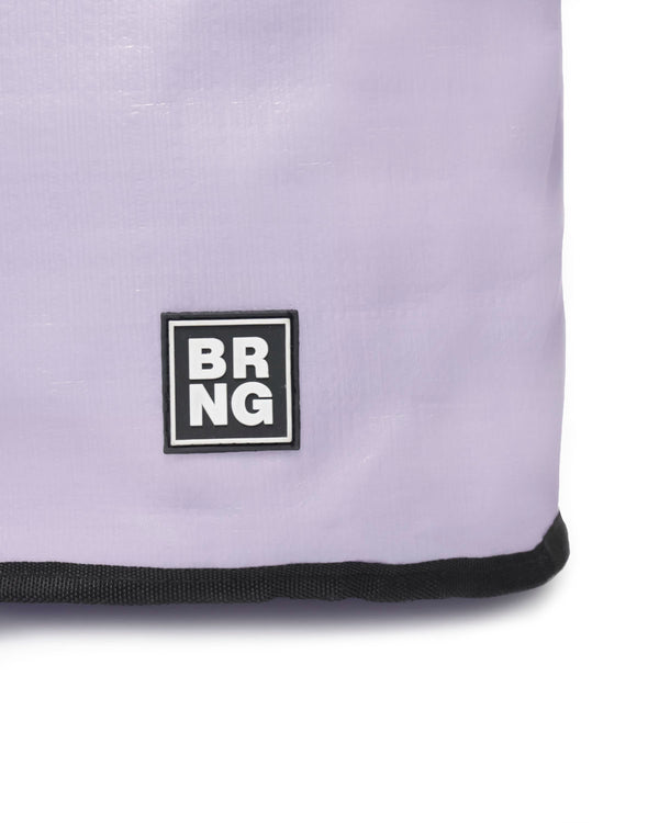 Close-up of The Brooke Tote by BRNG Bag in lavender, featuring a black-and-white square BRNG logo near the bottom corner and black trim along the edge, showcasing its stylish design.